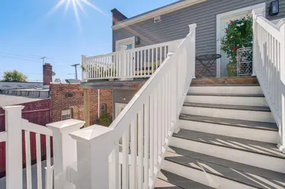 a house with a white staircase in front of a house at 7 Mi to Dtwn and Lake Erie Sleek Cleveland Apt! in Cleveland