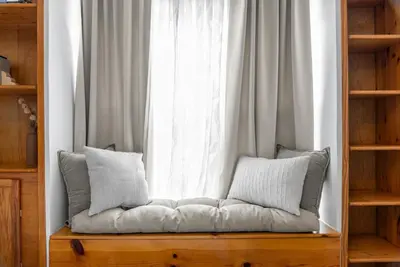 a couch with pillows sitting in front of a window at Wellness Retreat - Hot Tub Fire Pit Outdoor TV in Columbus