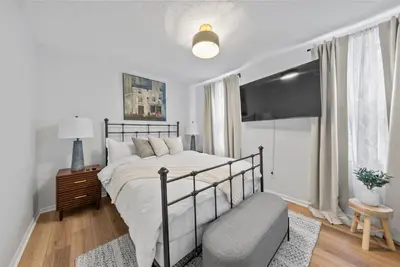 a white bedroom with a bed and a chair at Wellness Retreat - Hot Tub Fire Pit Outdoor TV in Columbus