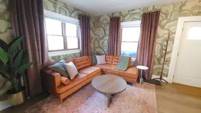 a living room with a couch and two windows at The Funky Fun Haus - Pickleball, Hot Tub, Arcade in Columbus