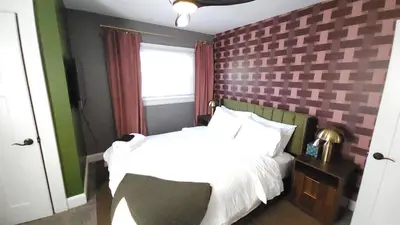 a bedroom with a white bed and a brick wall at The Funky Fun Haus - Pickleball, Hot Tub, Arcade in Columbus