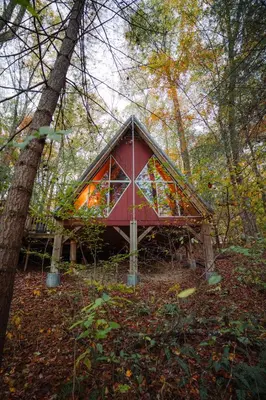 a red house in the middle of a forest at Waterfront A Frame with Dock Canoe Kayaks Family in Rockbridge
