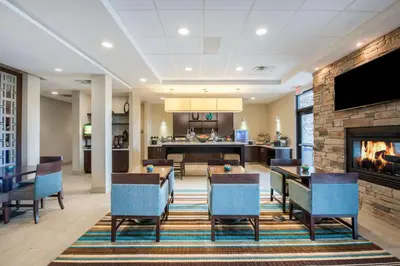 a lobby with a dining room and a fireplace at Hawthorn Suites by Wyndham Bridgeport in Bridgeport