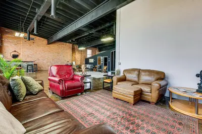 a living room with leather furniture and a brick wall at Walk to Huntington Center 5,000-Sq-Ft Dtwn Apt in Toledo