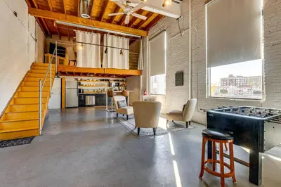 a large room with a staircase and chairs and a kitchen at Walk to Huntington Center 5,000-Sq-Ft Dtwn Apt in Toledo