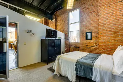 a bedroom with a bed and a brick wall at Walk to Huntington Center 5,000-Sq-Ft Dtwn Apt in Toledo