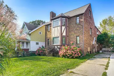 a large brick house with flowers in the yard at Striking Tudor Revival in Five Points District! in Toledo