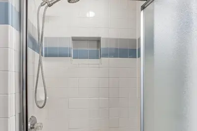 a shower with blue and white tiles in a bathroom at Striking Tudor Revival in Five Points District! in Toledo