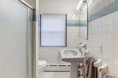 a bathroom with a sink and a toilet and a mirror at Striking Tudor Revival in Five Points District! in Toledo