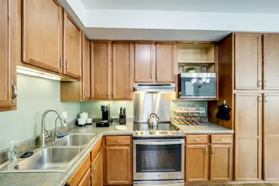 a kitchen with wooden cabinets and stainless steel appliances at Walk to UC and Hospitals! Cincy Home with Patio in Cincinnati
