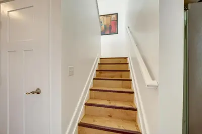 a staircase in a house with a white wall at Walk to UC and Hospitals! Cincy Home with Patio in Cincinnati