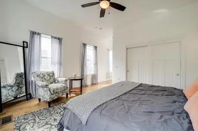 a bedroom with a bed and a chair and a ceiling fan at Walk to UC and Hospitals! Cincy Home with Patio in Cincinnati