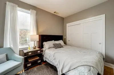 a bedroom with a bed and a chair and a window at Walk to UC and Hospitals! Cincy Home with Patio in Cincinnati