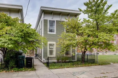 a green house with trees in front of it at Walk to UC and Hospitals! Cincy Home with Patio in Cincinnati