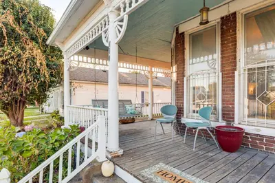 a porch of a house with two chairs and a table at 2 Blocks to Ohio River! Historic Victorian Gem in Gallipolis