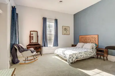 a bedroom with a bed and a chair and a mirror at 2 Blocks to Ohio River! Historic Victorian Gem in Gallipolis