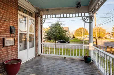 a porch of a brick building with a white door at 2 Blocks to Ohio River! Historic Victorian Gem in Gallipolis
