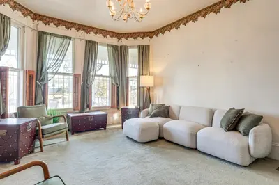 a living room with a couch and some windows at 2 Blocks to Ohio River! Historic Victorian Gem in Gallipolis