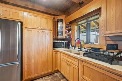 a kitchen with wooden cabinets and a stainless steel refrigerator at Sprinkle Bottom Lodge- 12 Acre Cabin, Pond, AC, Heating & Pet Friendly