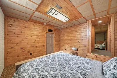 a bedroom with a bed in a room with wooden walls at Sprinkle Bottom Lodge- 12 Acre Cabin, Pond, AC, Heating & Pet Friendly