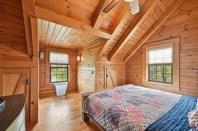 a bedroom in a log cabin with a bed at Sprinkle Bottom Lodge- 12 Acre Cabin, Pond, AC, Heating & Pet Friendly