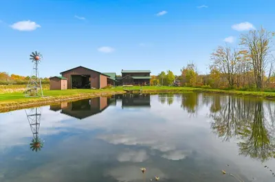 a large lake with a house and a windmill at Sprinkle Bottom Lodge- 12 Acre Cabin, Pond, AC, Heating & Pet Friendly