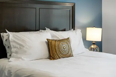 a white bed with white pillows and a gold pillow at Calaboose Retreat in Campton