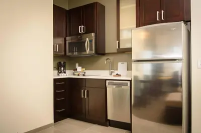 a kitchen with wooden cabinets and a stainless steel refrigerator at Residence Inn by Marriott Cleveland Avon at The Emerald Event Center in Avon