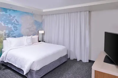 a bedroom with a white bed and a tv at Courtyard by Marriott Columbus Grove City in Grove City