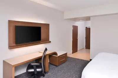 a hotel room with a desk and a tv at Courtyard by Marriott Columbus Grove City in Grove City