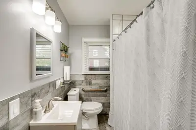 a white bathroom with a toilet and a shower at 1 Mi to Akron Zoo Ranch-Style Home with Yard! in Akron