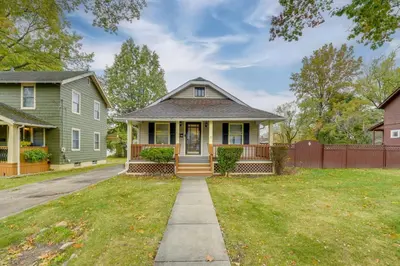 a green house with a porch and a fence at 1 Mi to Akron Zoo Ranch-Style Home with Yard! in Akron