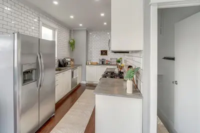 a kitchen with a stainless steel refrigerator and white cabinets at Pet-Friendly Oakley Gem with Large Backyard! in Cincinnati
