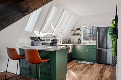 a kitchen with green cabinets and a counter with orange chairs at Hot-Tub Sauna Cold Plunge - Evergreen Escape in Campton