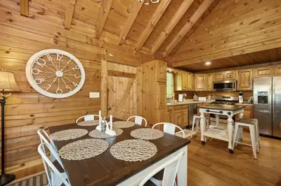 a kitchen with a table and chairs in a cabin at Hot Tub WiFi Firepit HazelBrook Haven in Hazel Green