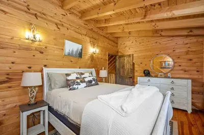 a bedroom with a bed in a log cabin at Hot Tub WiFi Firepit HazelBrook Haven in Hazel Green