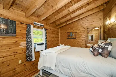 a bedroom with a bed in a log cabin at Hot Tub WiFi Firepit HazelBrook Haven in Hazel Green