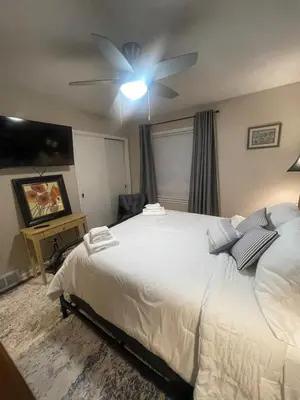 a bedroom with a large white bed with a ceiling fan at Newly renovated 3-bedroom lakeside home in Euclid