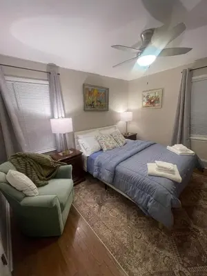 a bedroom with a bed and a chair and a ceiling fan at Newly renovated 3-bedroom lakeside home in Euclid