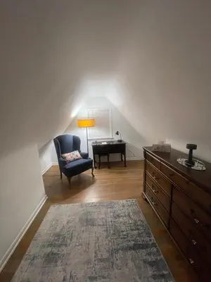 a living room with a blue chair and a desk at Newly renovated 3-bedroom lakeside home in Euclid
