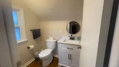 a bathroom with a toilet and a sink and a mirror at Newly renovated 3-bedroom lakeside home in Euclid