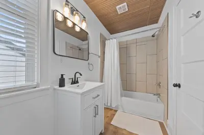 a white bathroom with a sink and a tub and a mirror at Watkins Complex in Covington