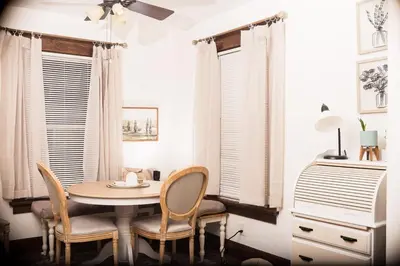 a dining room with a table and chairs and windows at Country cottage in Cheviot! in Cincinnati