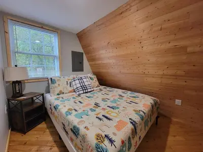 a bedroom with a bed with a wooden wall at A Frame of Mind - near Red River Gorge KY in Jeffersonville