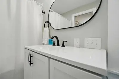 a white bathroom with a sink and a mirror at Carriage House Retreat 1 in Milford
