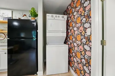 a black refrigerator in a kitchen with a floral wallpaper at Carriage House Retreat 1 in Milford