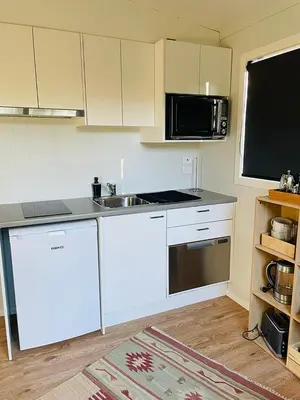 a kitchen with white cabinets and a sink and a microwave at The Travellers Tiny Hideaway in Cincinnati