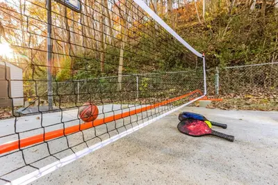 a tennis racket laying on the ground next to a net at Spring Lovers Retreat Sauna, Hot Tub & Firepit in South Bloomingville