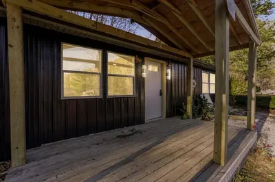 a wooden porch with a white door and windows at Spring Lovers Retreat Sauna, Hot Tub & Firepit in South Bloomingville