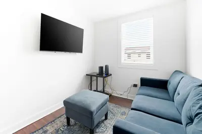 a living room with a blue couch and a stool at Contemporary Private En-Suite - Steps to Cleveland Clinic in Cleveland